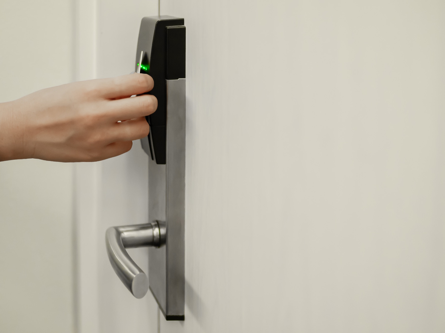 Hand presenting an access card to an electronic door lock